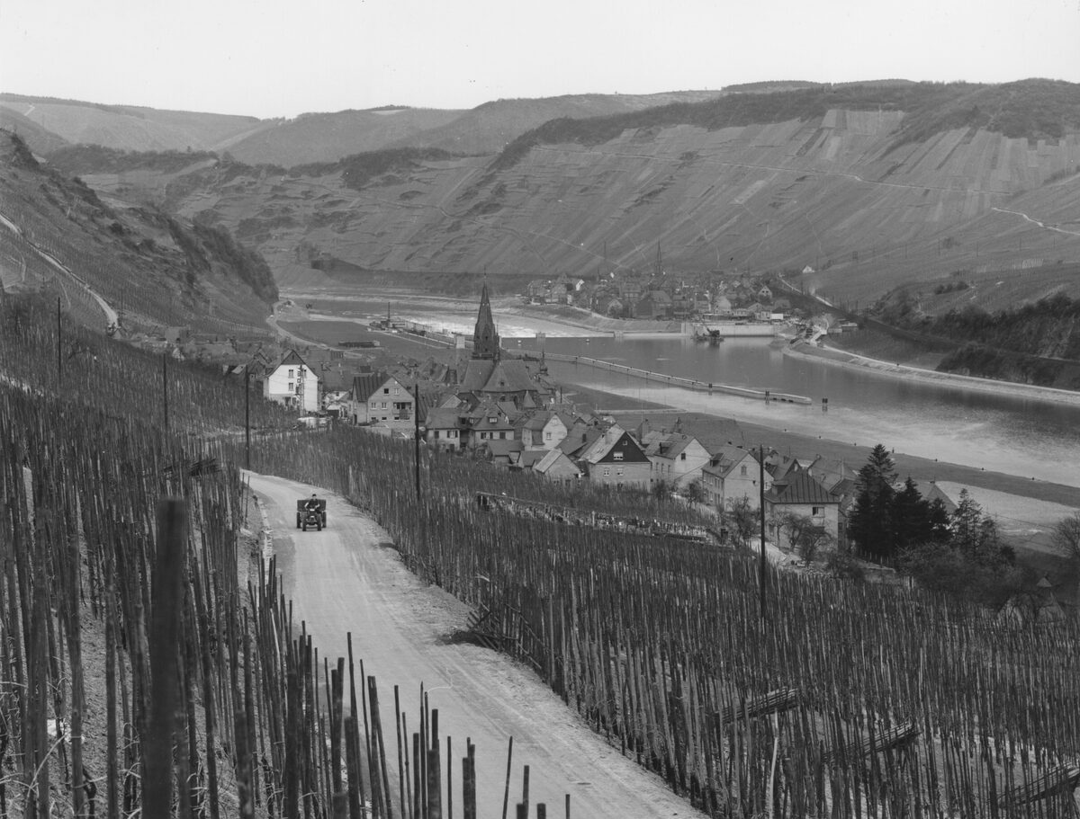 Historische Ortsansicht von Sankt Aldegund mit Weinbergen, Mosel und Ortskern während der Zeit des Staustufenbaus.