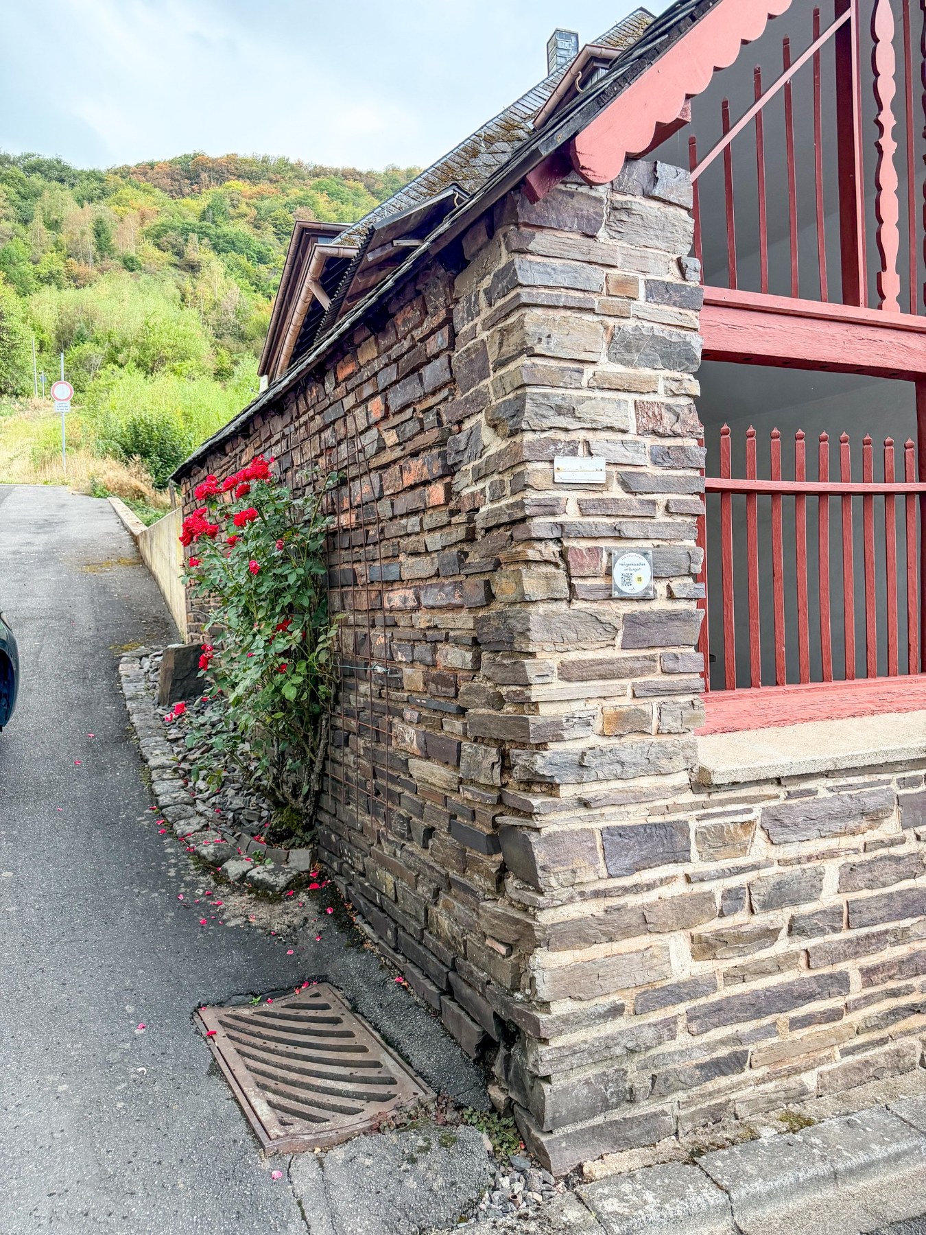 Schräger Blick auf Bruchsteinmauerwerk und offene rote Holzfront der Kapelle.