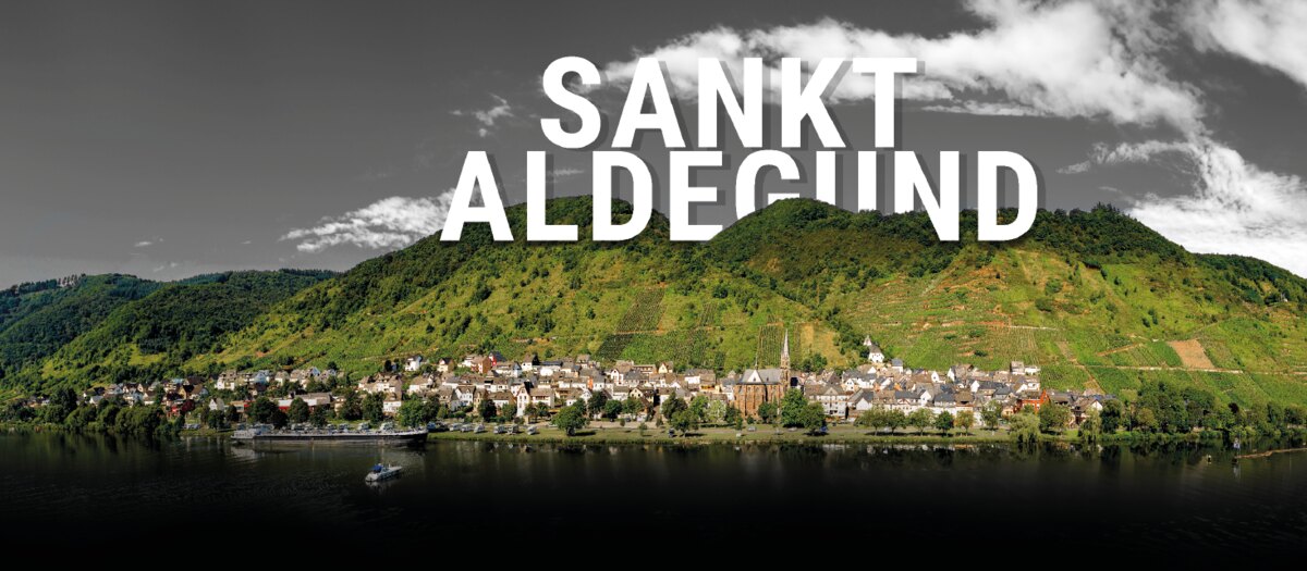 Panoramaansicht von Sankt Aldegund an der Mosel mit Ortskern und Weinbergen am Hang.